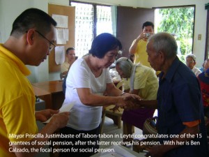 Mayor Priscilla Justimbaste of Tabon-tabon in Leyte congratulates one of the 15 grantees of social pension, after the latter receives his pension. With her is Ben Calzado, the focal person for social pension.